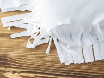 Making homemade Easter decorations: tying the fringes on your cushion cover.