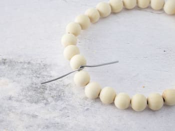 Making a homemade Easter wreath: threading wooden balls onto the piece of wire.