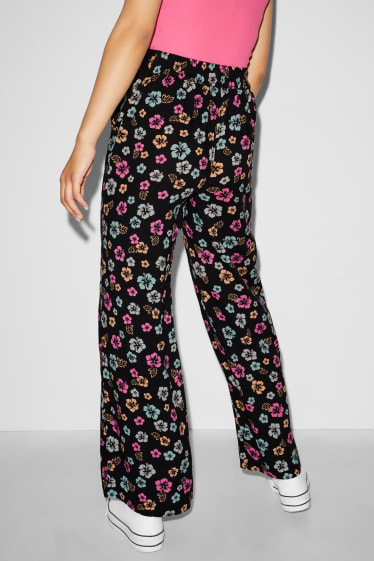 Nastolatki - CLOCKHOUSE - spodnie materiałowe - wysoki stan - szerokie nogawki - w kwiatki - czarny