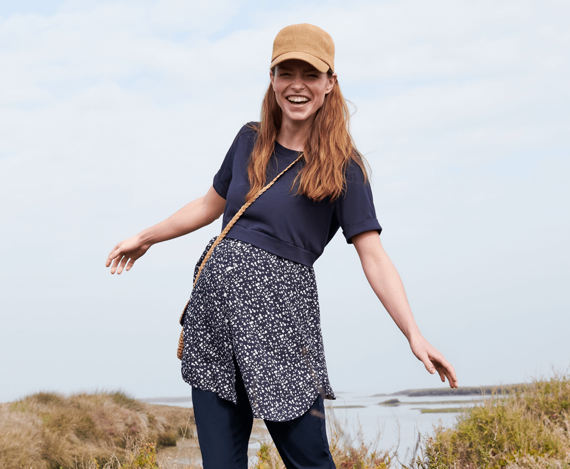 Een lachende vrouw aan het begin van haar zwangerschap in een hippe outfit. 