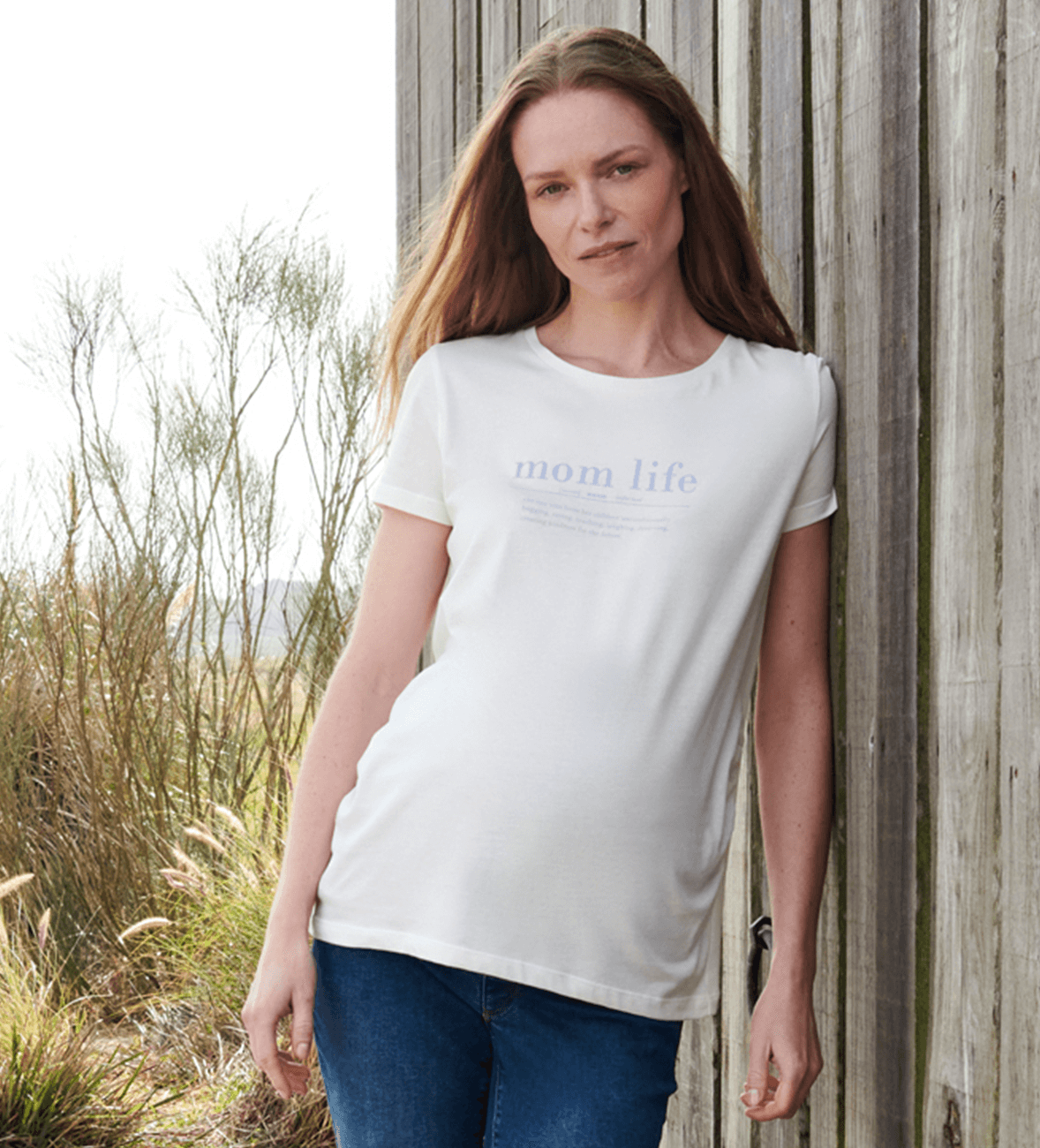 Een zwangere vrouw in haar derde trimester draagt een zwangerschapsjeans en een casual T-shirt.