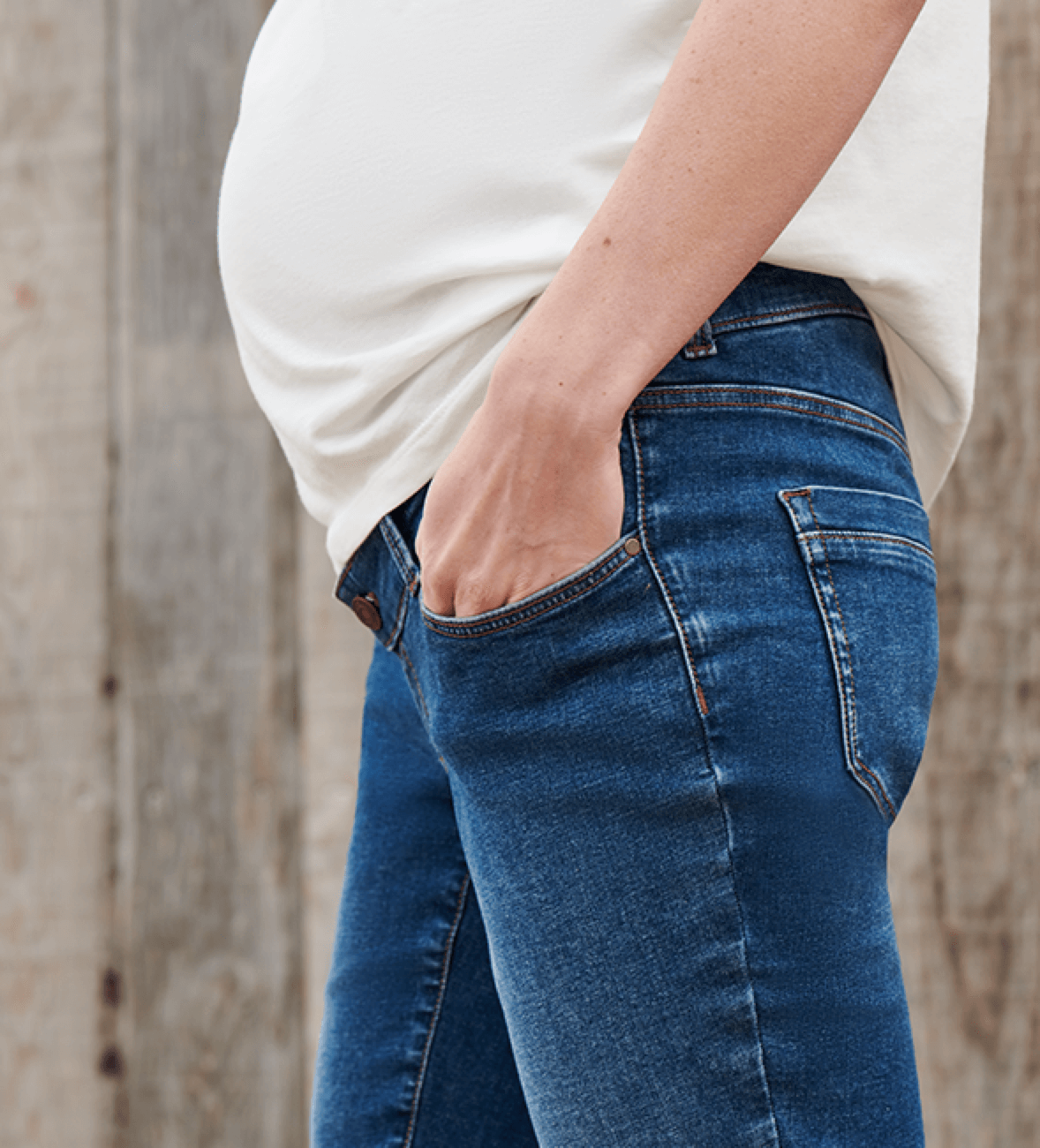 Close-up van een zwangerschapsjeans gecombineerd met een casual, wit T-shirt. 