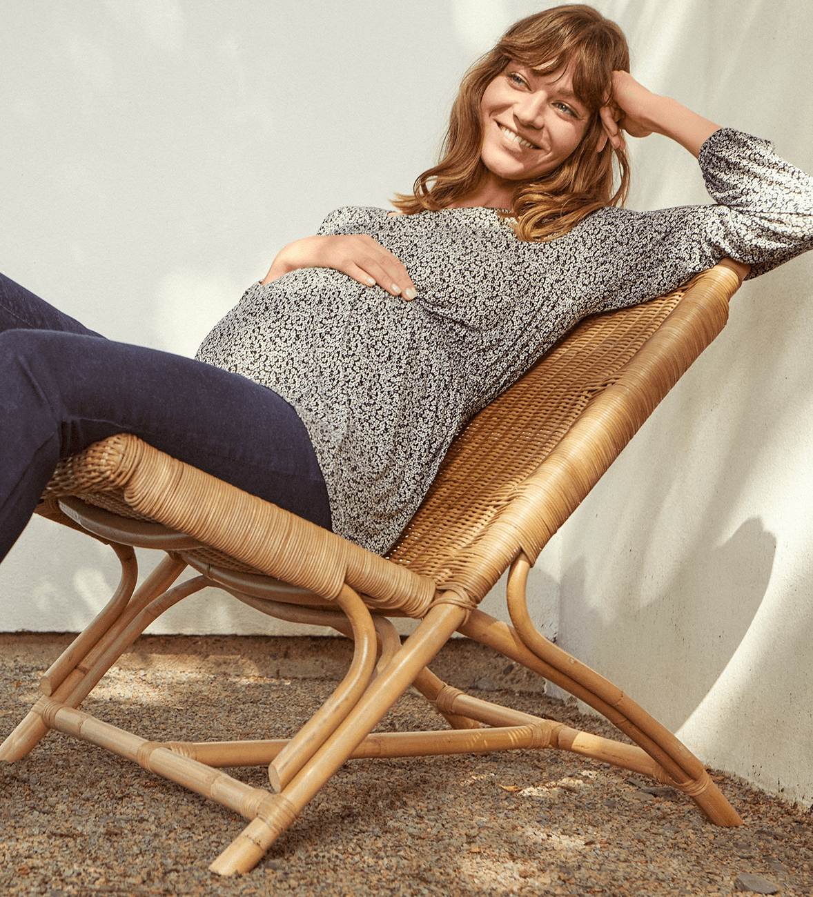 A pregnant woman relaxes on a sun lounger in a comfortable maternity shirt.