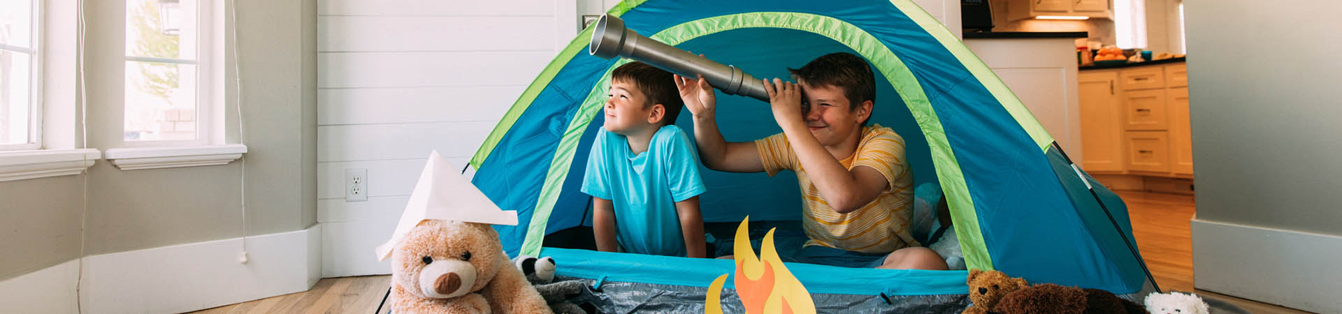 Activité d’intérieur : des enfants jouent au camping dans le salon.