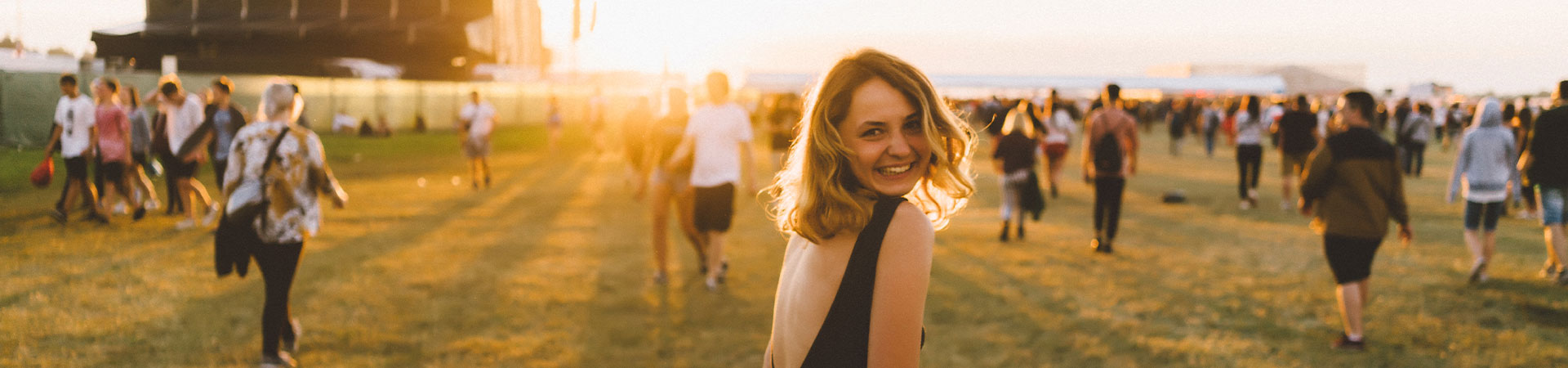 A young woman walking over a field at a festival.