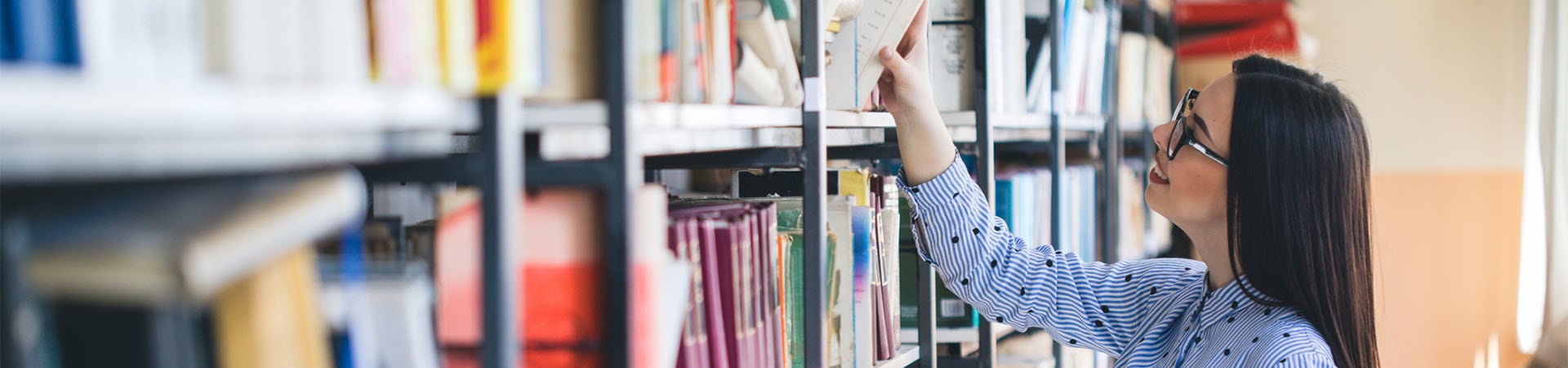 Plezier bij het leren - vrouw zoekt geschikte boeken voor haar bijscholing.