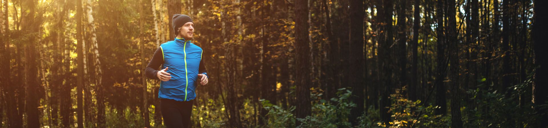 Running in autumn: man jogging on a forest path.