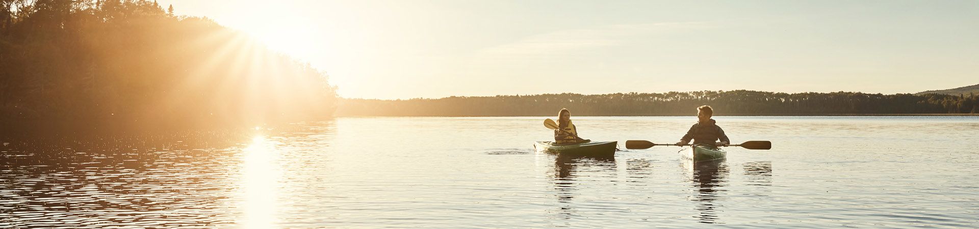 Kanoën – Jong stel in eenpersoonskano’s op een meer.