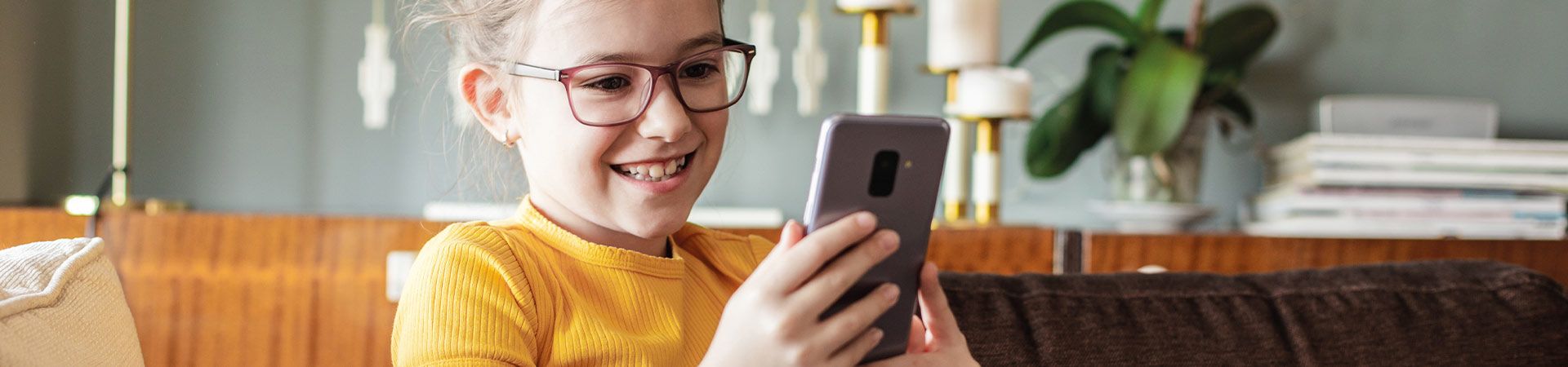 Pierwszy smartfon dla dziecka: dziewczynka cieszy się z możliwości, jakie daje jej telefon komórkowy.