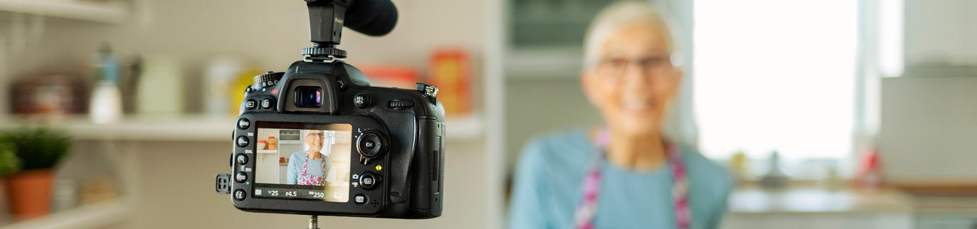 Activités pour personnes âgées : une dame se tient devant la caméra et tourne une vidéo de cuisine.