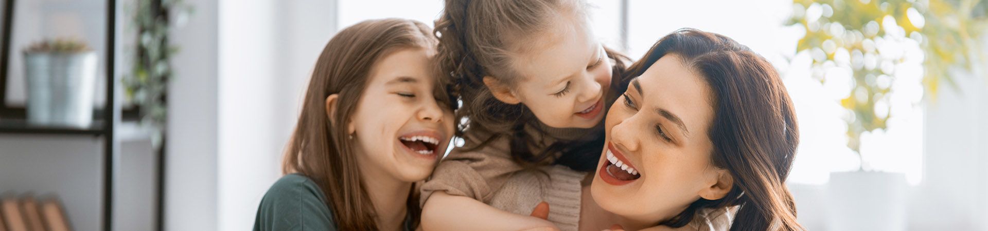 Spiele bei Regenwetter drinnen – Mutter und Töchter spielen auf dem Sofa.