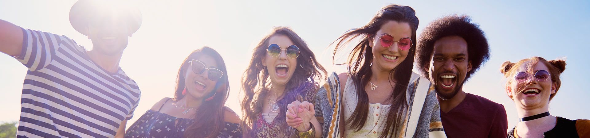 A Group of friends wearing summer festival outfits as they walk across the festival grounds.