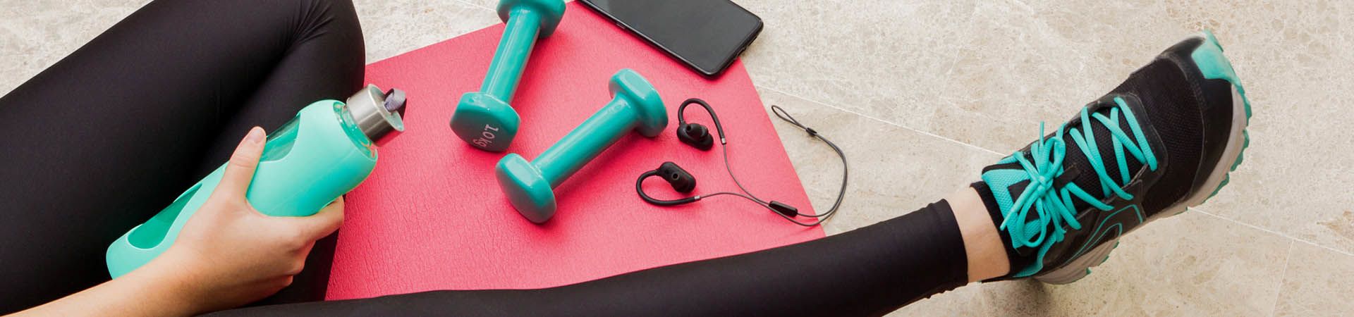 Close-up of fitness accessories: yoga mat, small dumbbells, sports clothing.