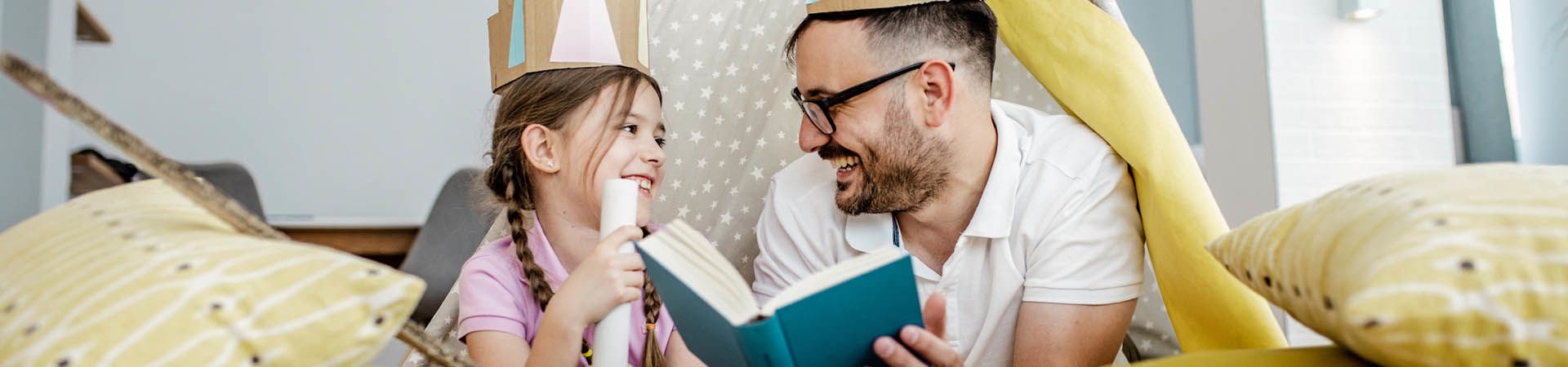 Kindern vorlesen: Ein Vater liest seiner Tochter eine Märchen-Geschichte vor.