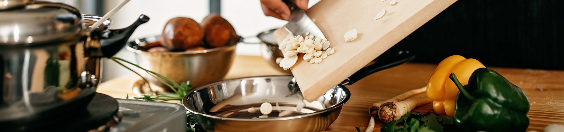 Apprendre à cuisiner : un cuisinier amateur dépose des ingrédients dans une poêle.