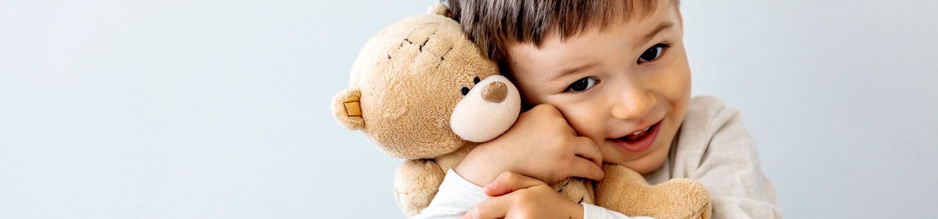 Speelgoed kinderen - Jongen knuffelt met zijn teddybeer.
