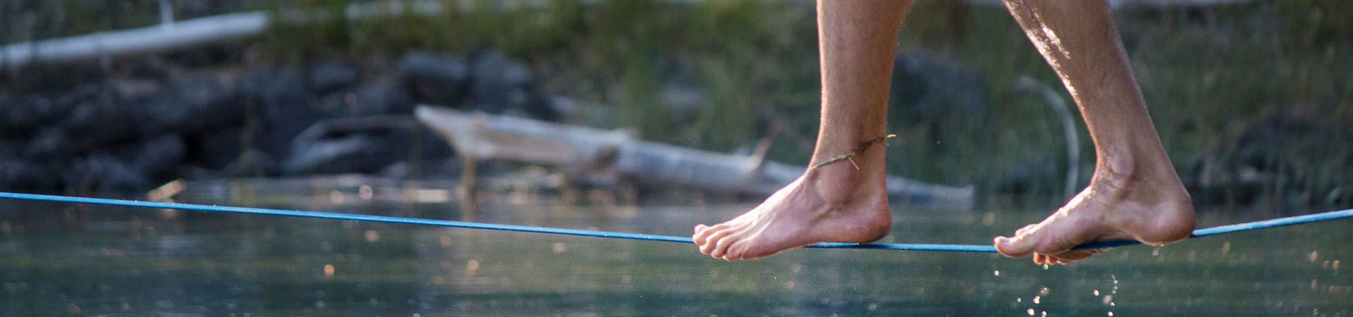 Slackline – Un uomo è in equilibrio su una waterline sospesa su un corso d’acqua.