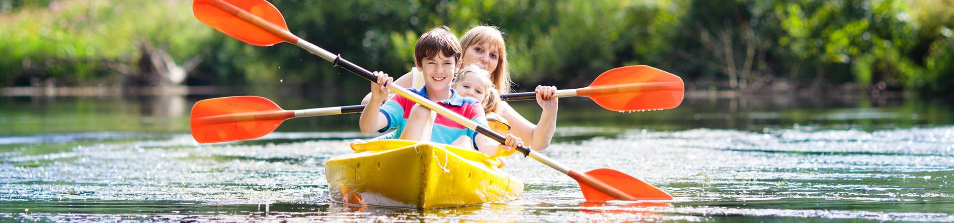 Actividades al aire libre en familia: una madre y sus hijos van en kayak.