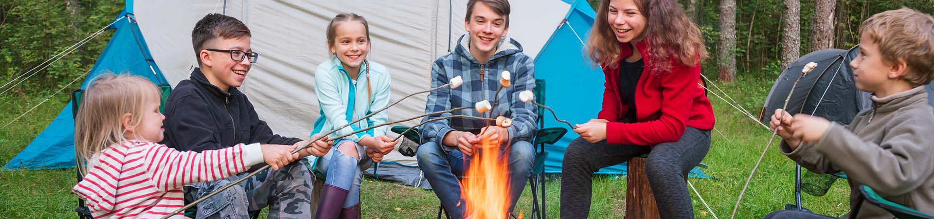 Ferienlager – Kinder grillen Marshmallows über einem Lagerfeuer.