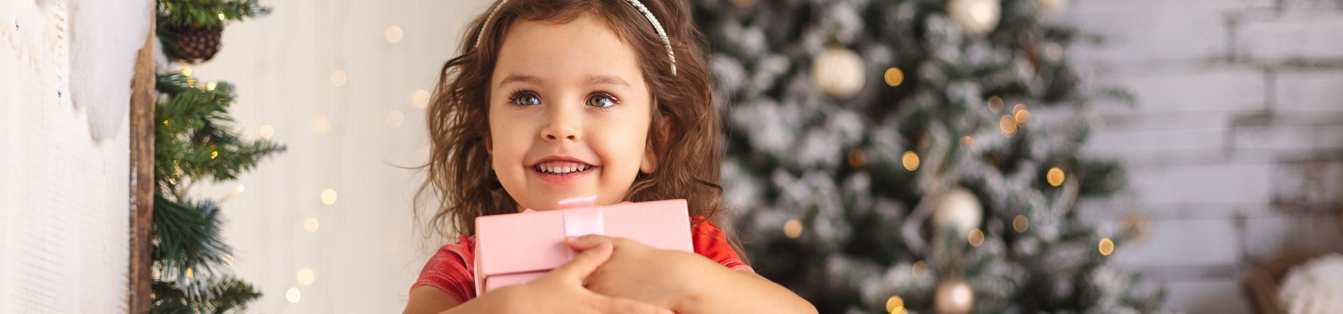 Christmas gifts for girls – a young girl holding her Christmas present.