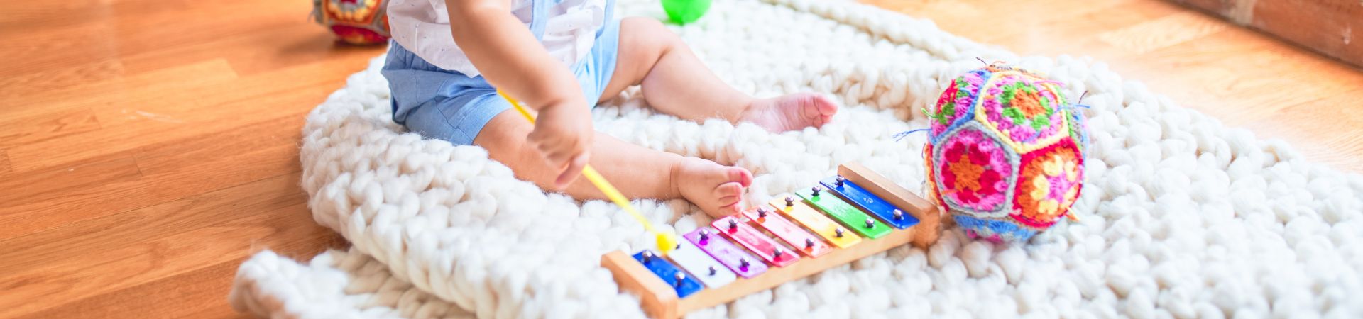 Gift for 2-year-old: toddler sits on the floor and plays the xylophone.