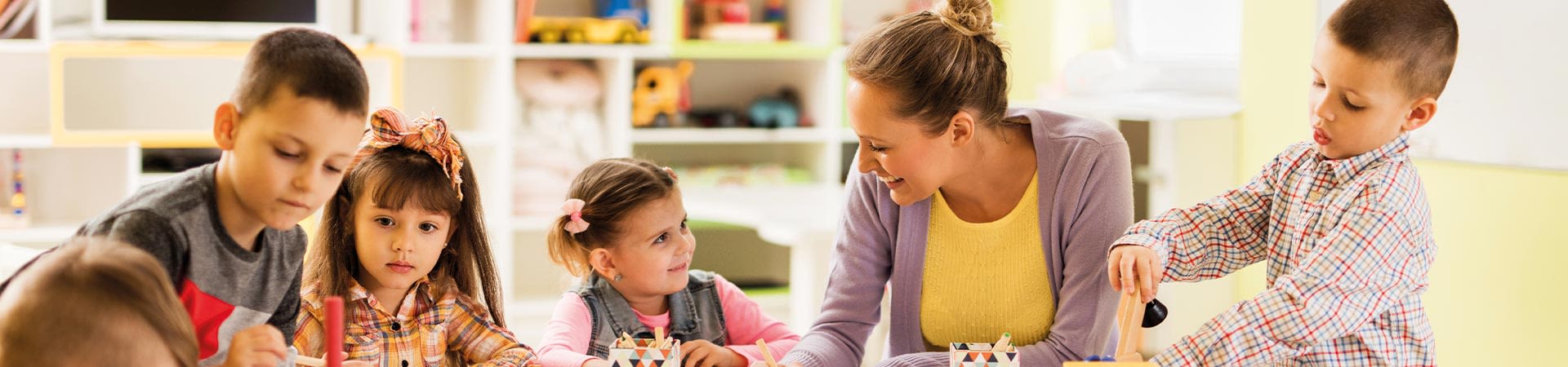 Kindergarten – Gruppe malt und spielt am Tisch.