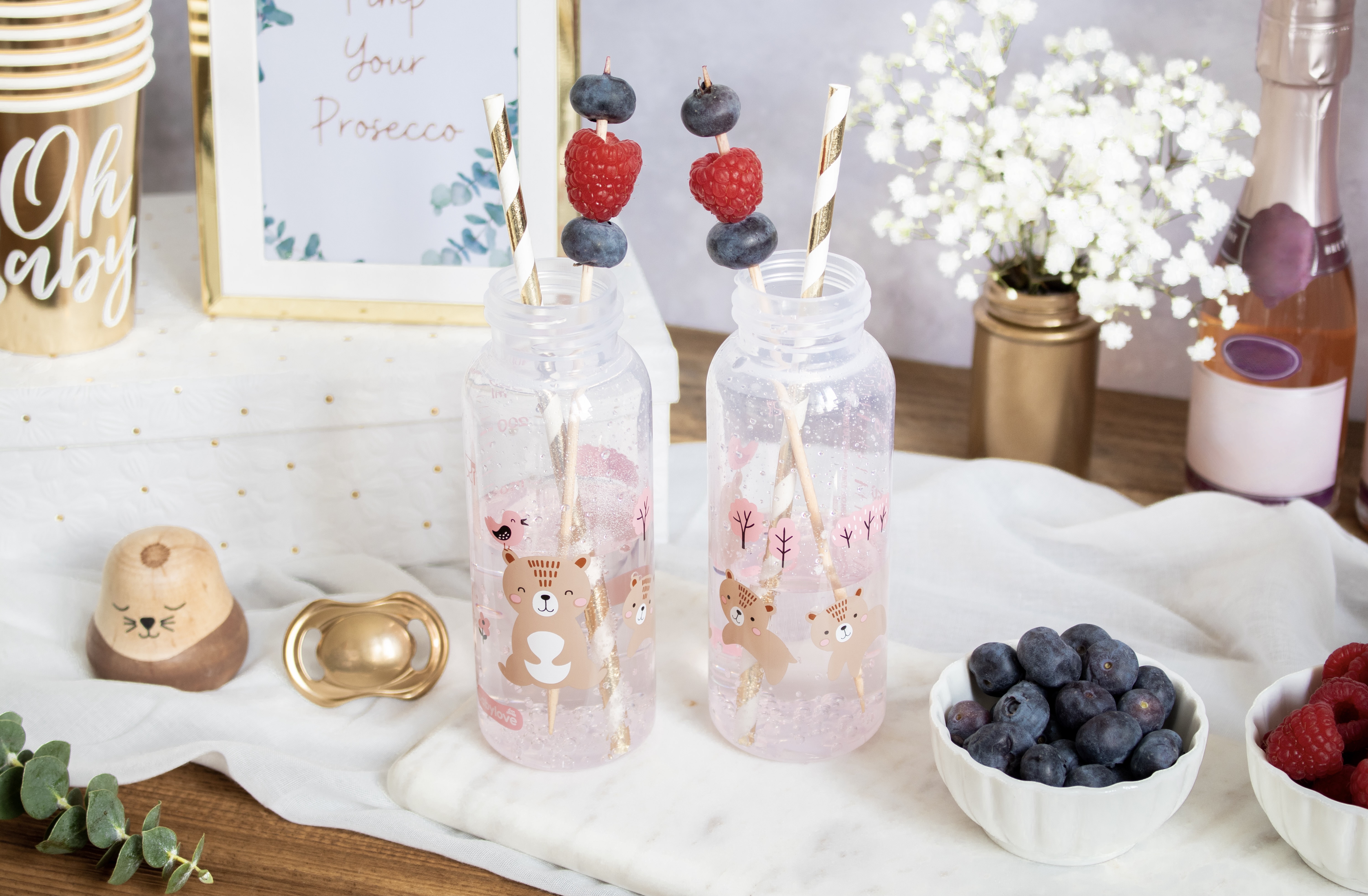 Roze limonade met besjes en bloesem in een babyflesje. Roze limonade met besjes en bloesem in een babyflesje.