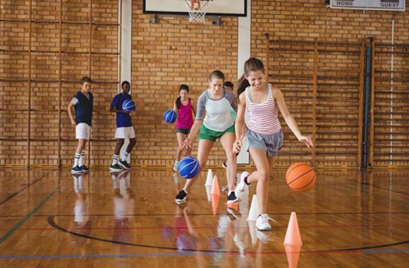 Chicos y chicas juegan juntos a baloncesto.