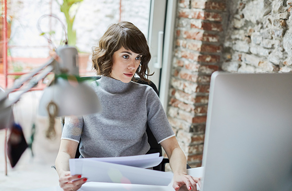 Richtig bewerben – Junge Frau sammelt Unterlagen, um ihre Bewerbung zu schreiben.