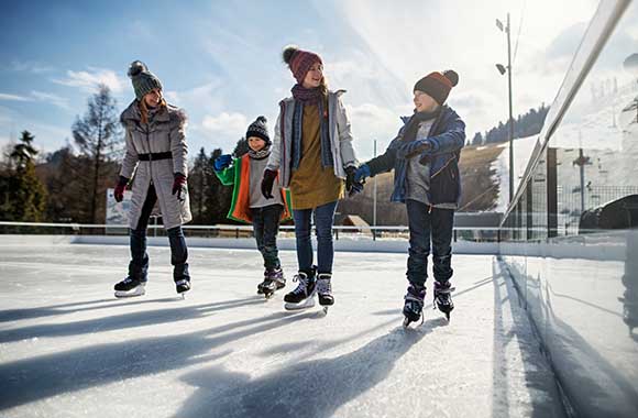 Moeder schaatst met kinderen op de schaatsbaan