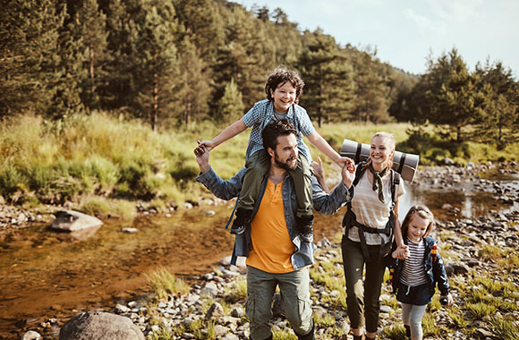 Parents hiking with kids along a stream.