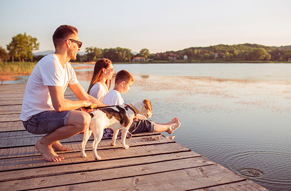 Familie zit bij zonsondergang aan het water Familie zit bij zonsondergang aan het water
