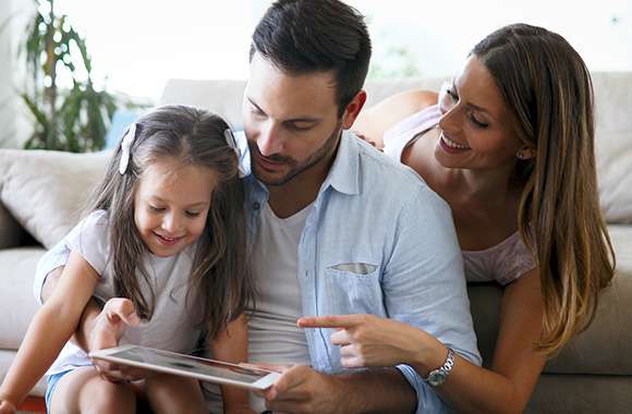 Bambini e tecnologia: genitori mostrano alla figlia un tablet.