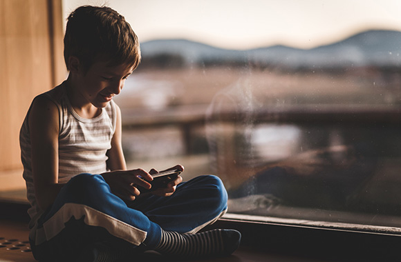 Chłopiec gra na telefonie komórkowym – gry mobilne są coraz bardziej popularne