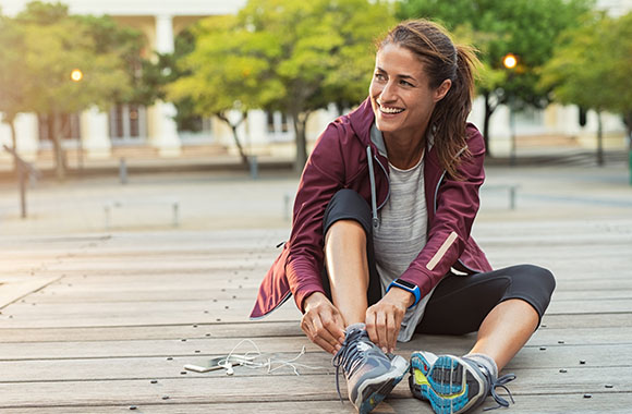 Staying healthy with jogging - Woman ties her running shoes. Staying healthy with jogging - Woman ties her running shoes.