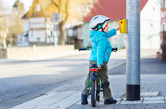 Un petit garçon en vélo appuie sur le bouton pour les piétons