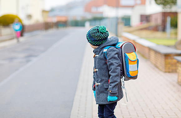 Dziecko w wieku szkolnym rozgląda się przed przejściem przez jezdnię