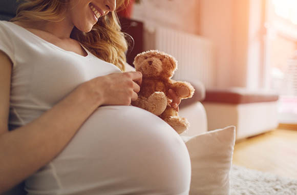 Una donna incinta tiene in mano un orsetto di peluche. Una donna incinta tiene in mano un orsetto di peluche.