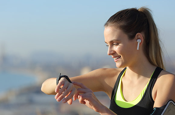 Training goals for beginners: Woman checks her pulse with a sports watch during running training.
