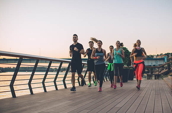 Running plan for beginners: a group of runners jogging together over a bridge.