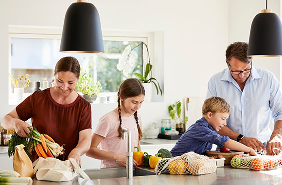 Living plastic free: family unpacking their shopping out of reusable carrier bags.