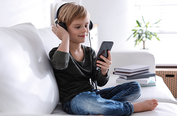 Kindveilige mobiele telefoons - jongen luistert naar muziek op zijn smartphone.