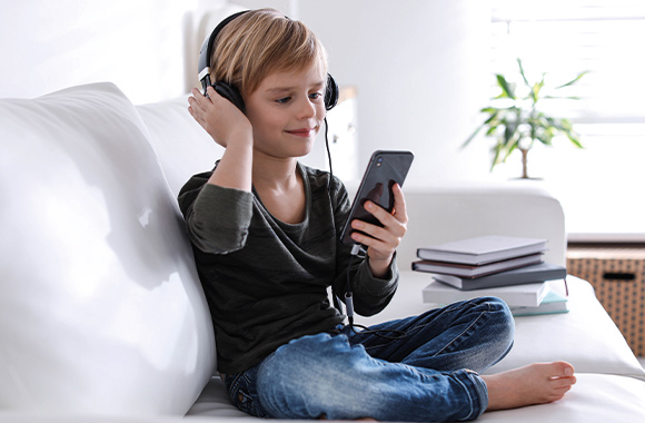 Najlepszy telefon dla dziecka: chłopiec słucha ulubionej muzyki na swoim pierwszym smartfonie. Najlepszy telefon dla dziecka: chłopiec słucha ulubionej muzyki na swoim pierwszym smartfonie.
