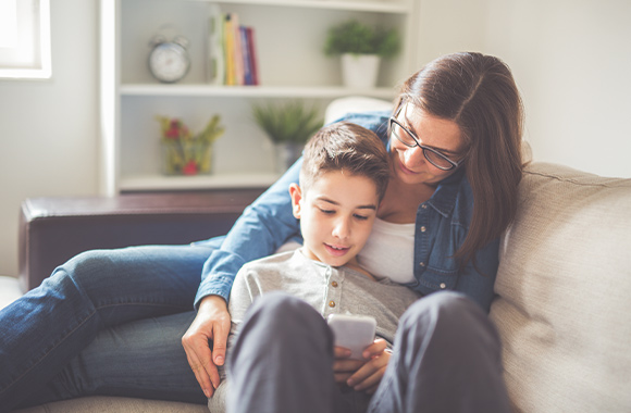 De eerste smartphone van een kind - moeder en zoon zijn samen bezig met de nieuwe smartphone.