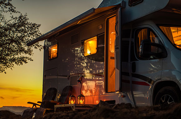 Wakacje w kamperze – samochód kempingowy na polu kempingowym podczas zachodu słońca.