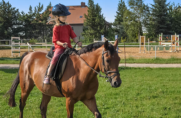 Une fille à dos de cheval pendant un cours d‘équitation.