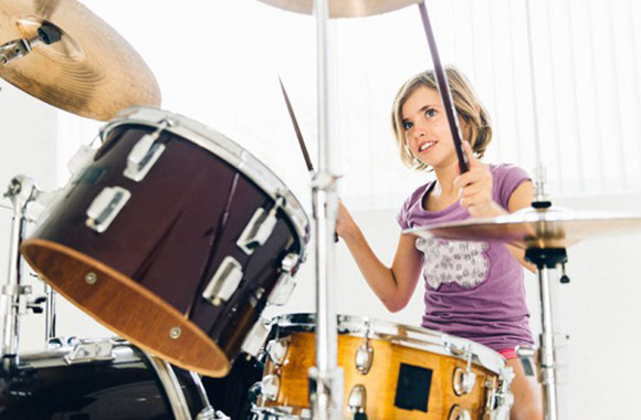 Instrumentos musicales: una niña toca la batería Instrumentos musicales: una niña toca la batería