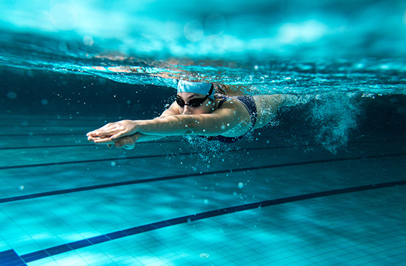 Schwimmsport – Schwimmerin taucht ins Wasser.