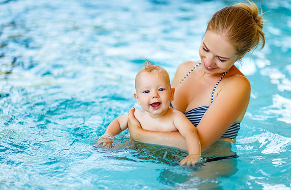 Happy baby held by mum in the swimming pool. Happy baby held by mum in the swimming pool.