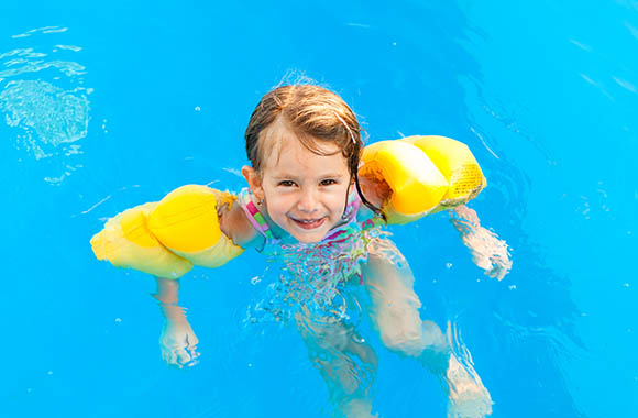 Girl swimming with water wings in a non-swimmer area of the indoor pool. Girl swimming with water wings in a non-swimmer area of the indoor pool.